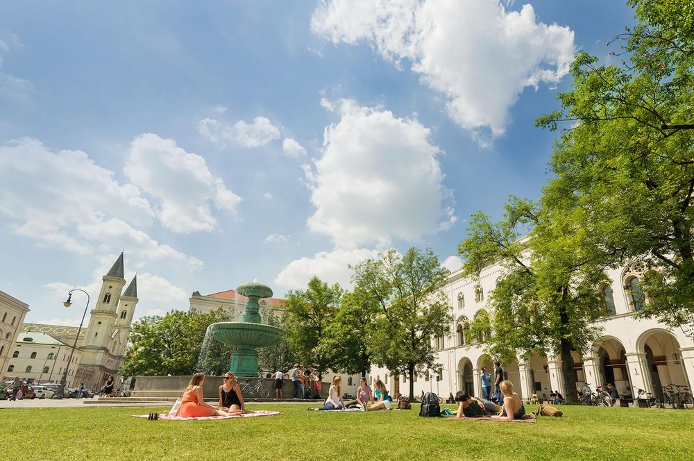 Picture of the main campus of the LMU Munich with students sitting on the grass and talking