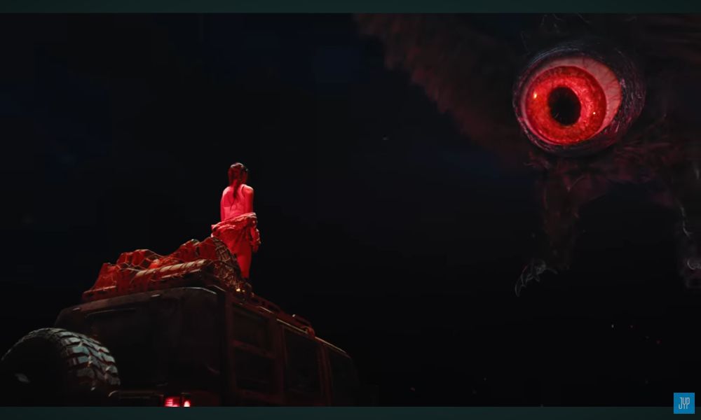 Print dos últimos segundos de Girls Will Be Girls, do Itzy, mostrando um pássaro gigante cuja cabeça tem apenas um olho enorme e vermelho