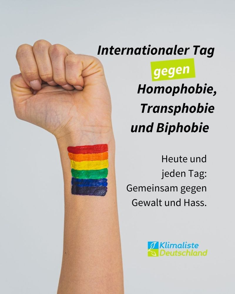 Schlagzeile: "Internationaler Tag gegen Homophobie, Transphobie und Biphobie." Das Wort "gegen" ist in weiß geschrieben und frühlingsgrün hinterlegt. Das Bild zeigt den Arm einer Person, der zur Faust geballt ist. Auf dem Handgelenk sind horizontal sechs bunte Streifen abgebildet, die so eine Regenbogenfahne ähneln. Darunter steht der Text: " Heute und jeden Tag; Gemeinsam gegen Gewalt und Hass."
