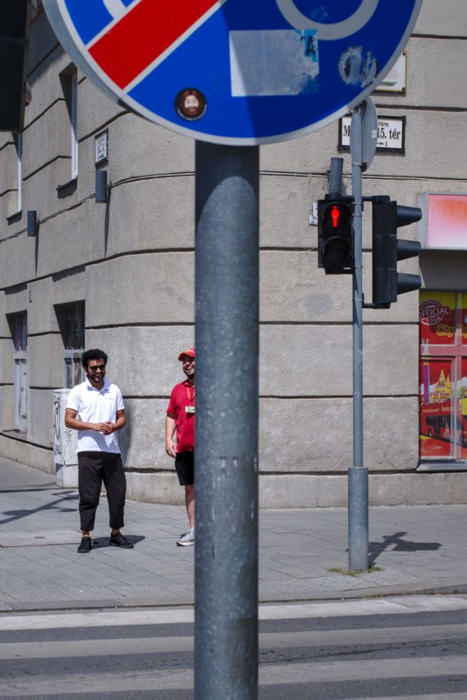 Two persons laughing behind a traffic sign
