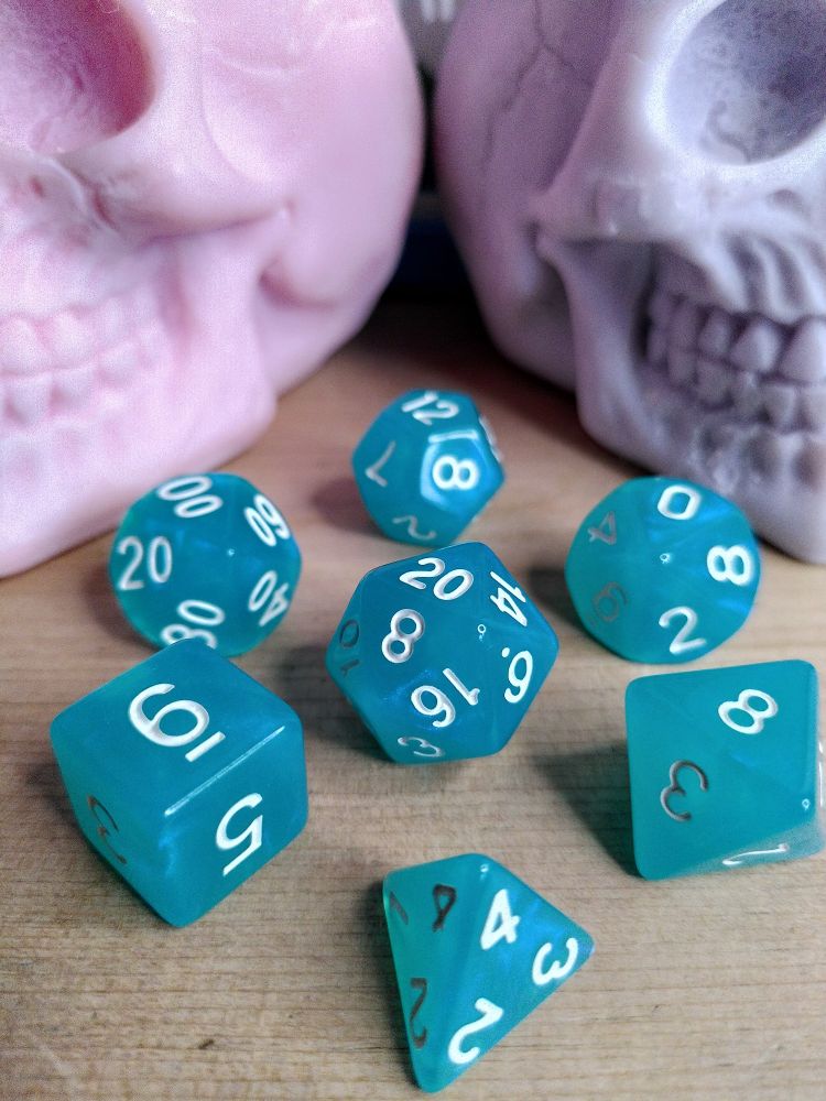 A transluscent set of seven turquoise TTRPG dice with white numbers and an iridescent mica powder sheen