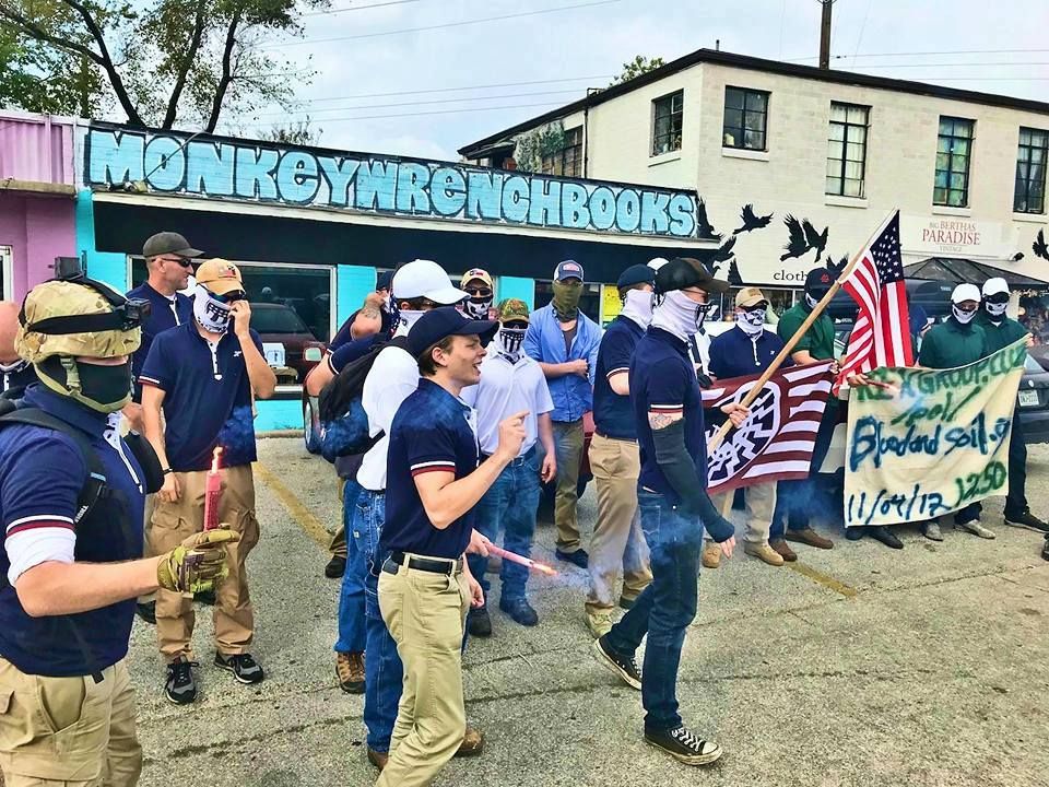 Thomas Rousseau and group marching downtown with a Vanguard America flag and a banner advertising the Patriot Front website
