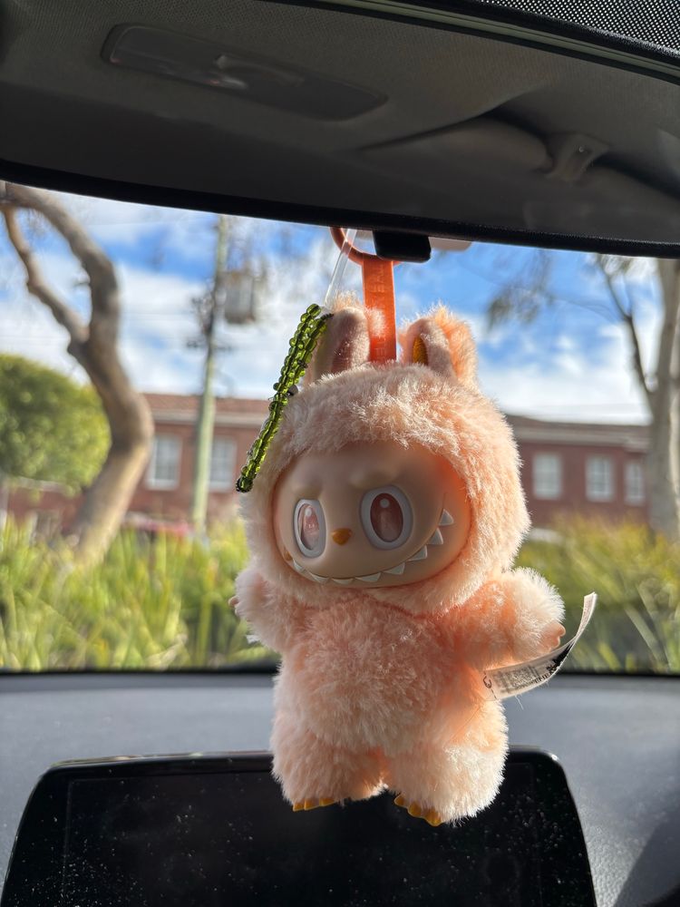happiness labubu hanging from a rearview mirror