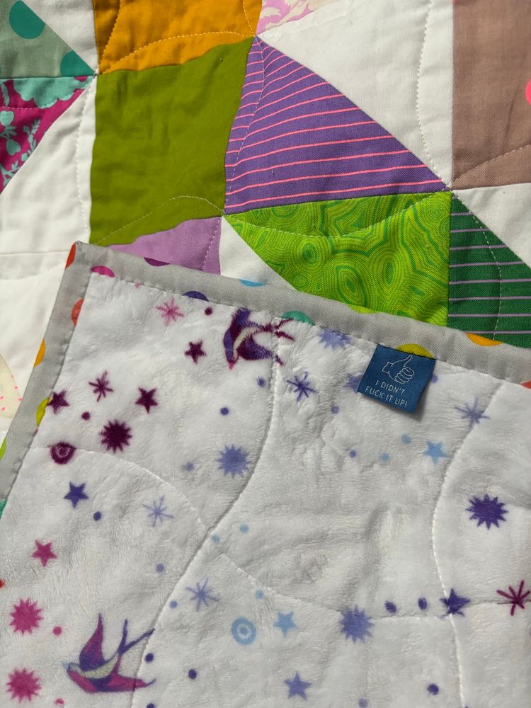 a back corner of the quit showing a blue label with a thumbs up that says “i didn’t fuck it up!”