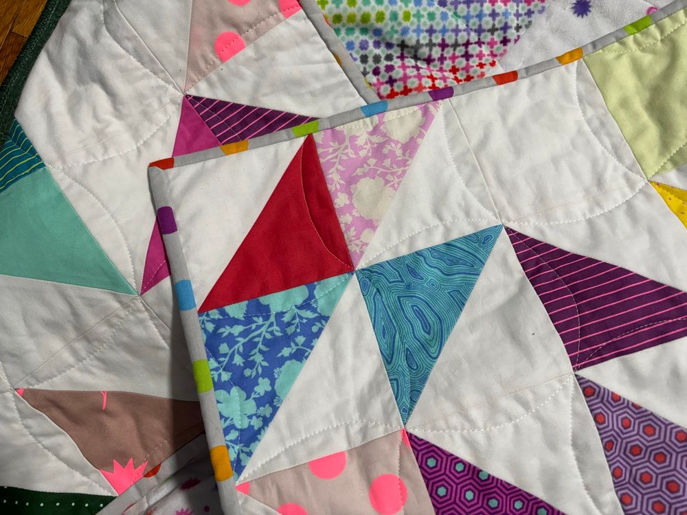 closer shot of the quilt so you can see the binding is a light grey with rainbow dots.