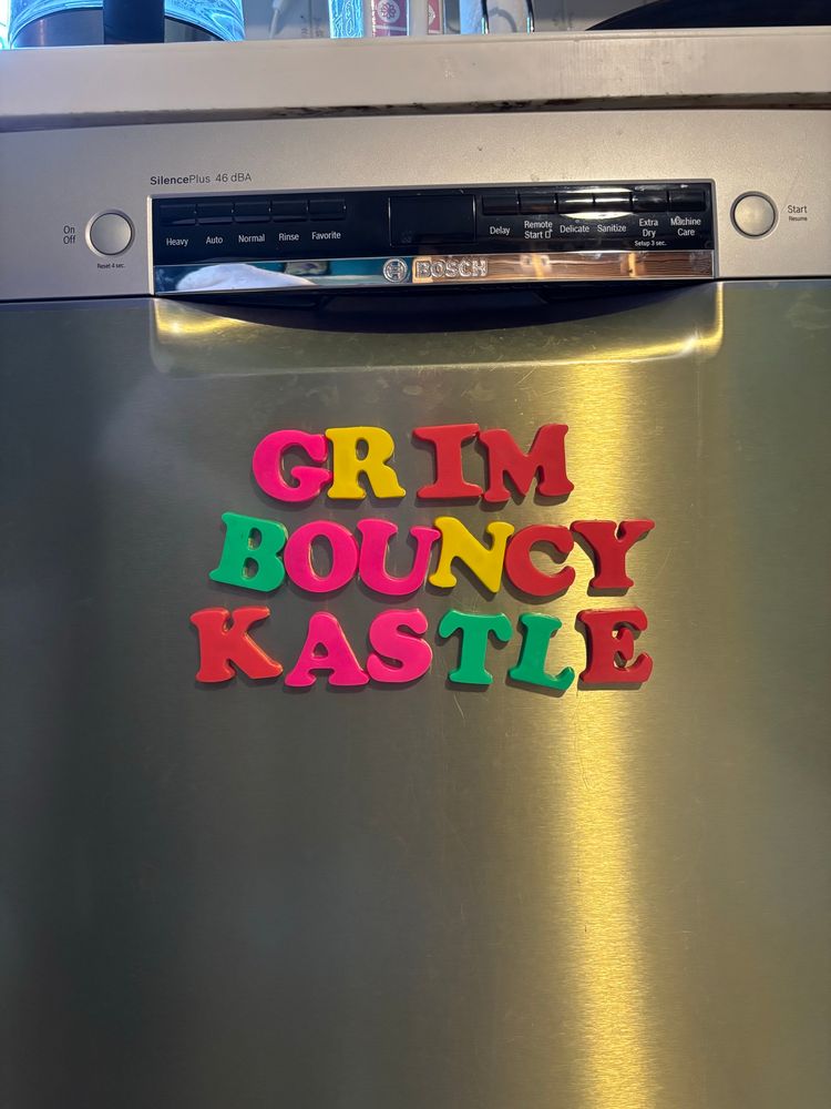 alphabet magnets on a dishwasher spelling “grim bouncy kastle”