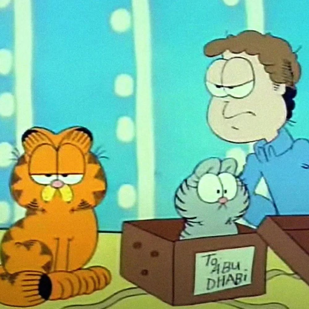 Garfield and Jon overlooking a box labelled “Abu Dhabi” with Nermal inside