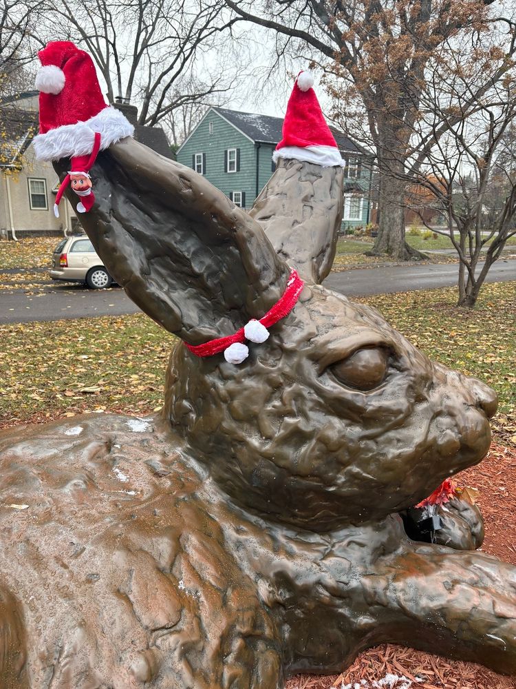 The Minnehaha Bunny sculpture decorated with three hats an an upside-down plush figure known as an Elf on the Shelf