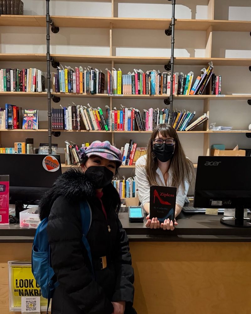 Catherine Lewis standing with Patricia Massy at the Massy Books counter. Patricia is holding the chapbook ZIPLESS.