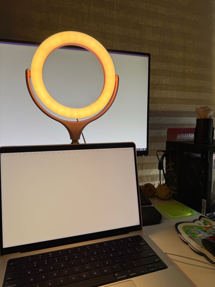 Catherine Lewis’s desk holding a MacBook, a ring light, a keyboard, and a monitor.