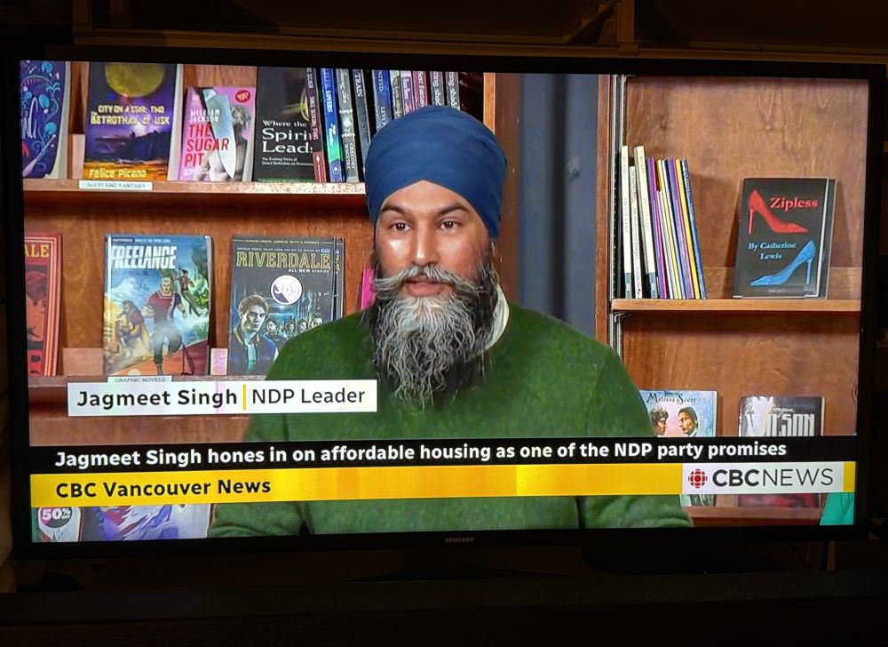 On CBC Vancouver News, New Democratic Party Leader Jagmeet Singh is seated in front of bookshelves. ZIPLESS is displayed on a shelf behind Singh’s left shoulder.