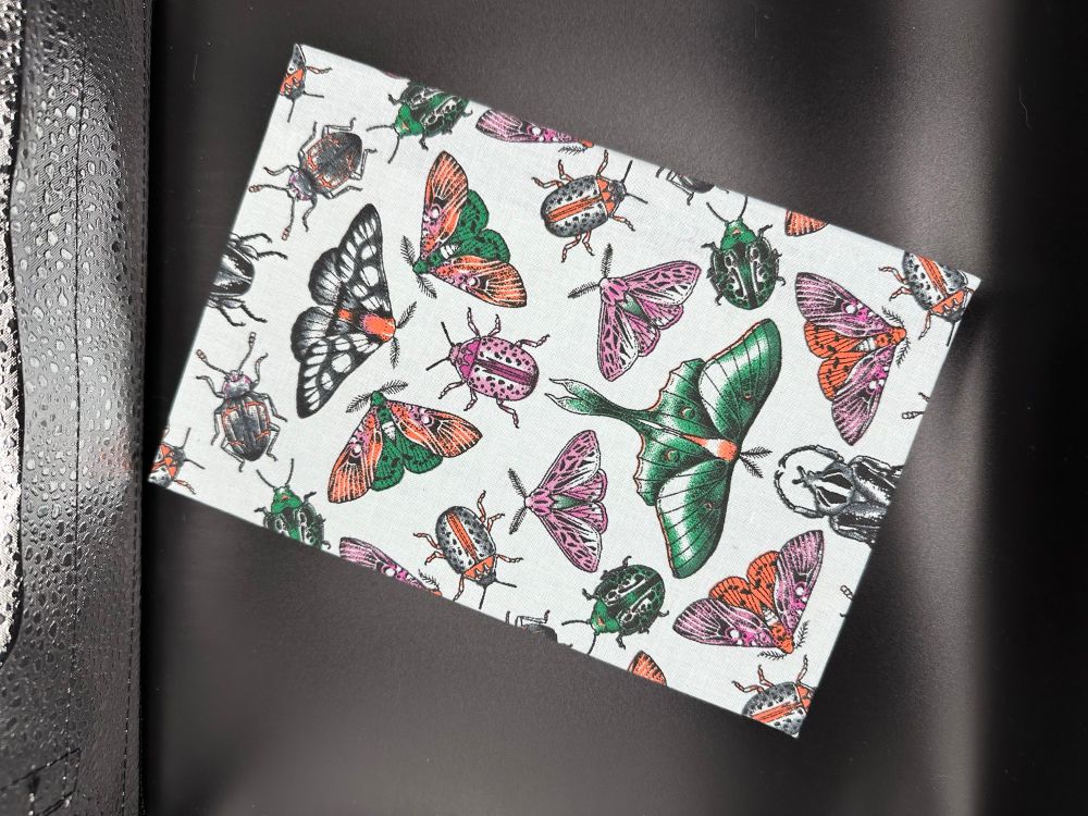 Another image of the book covered in symmetrical insect fabric, featuring a lunar moth. 