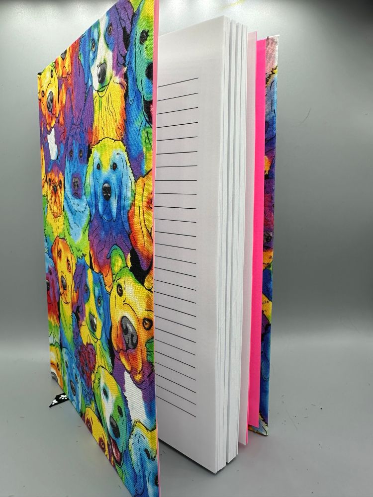 A colorful book, sitting open. The cover is rainbow dogs while it’s open showing the lined pages. 