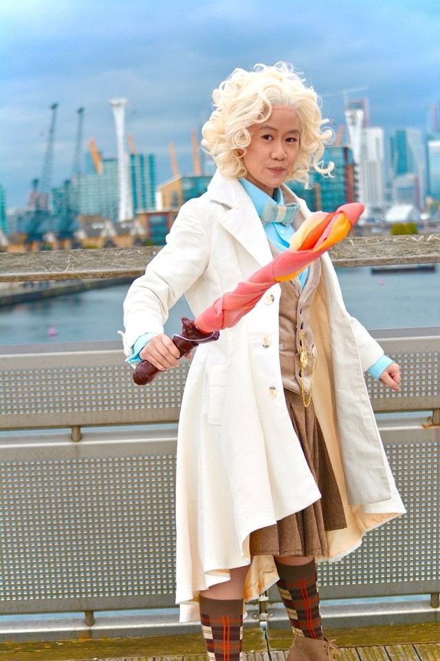 Fem presenting modern Aziraphale wearing a brown pleated skirt and knee high tartan socks with heeled boots, brandishing a flaming sword.