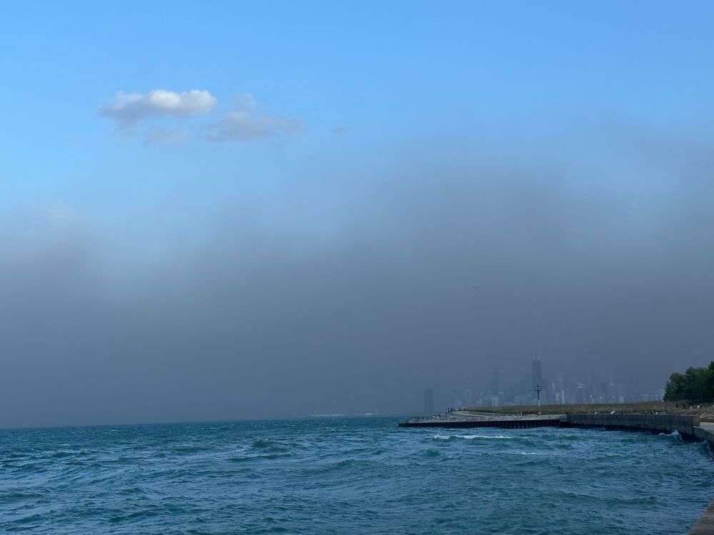 Gray clouds on the horizon obscure the skyline. Blue sky is higher up. The blue lake below.