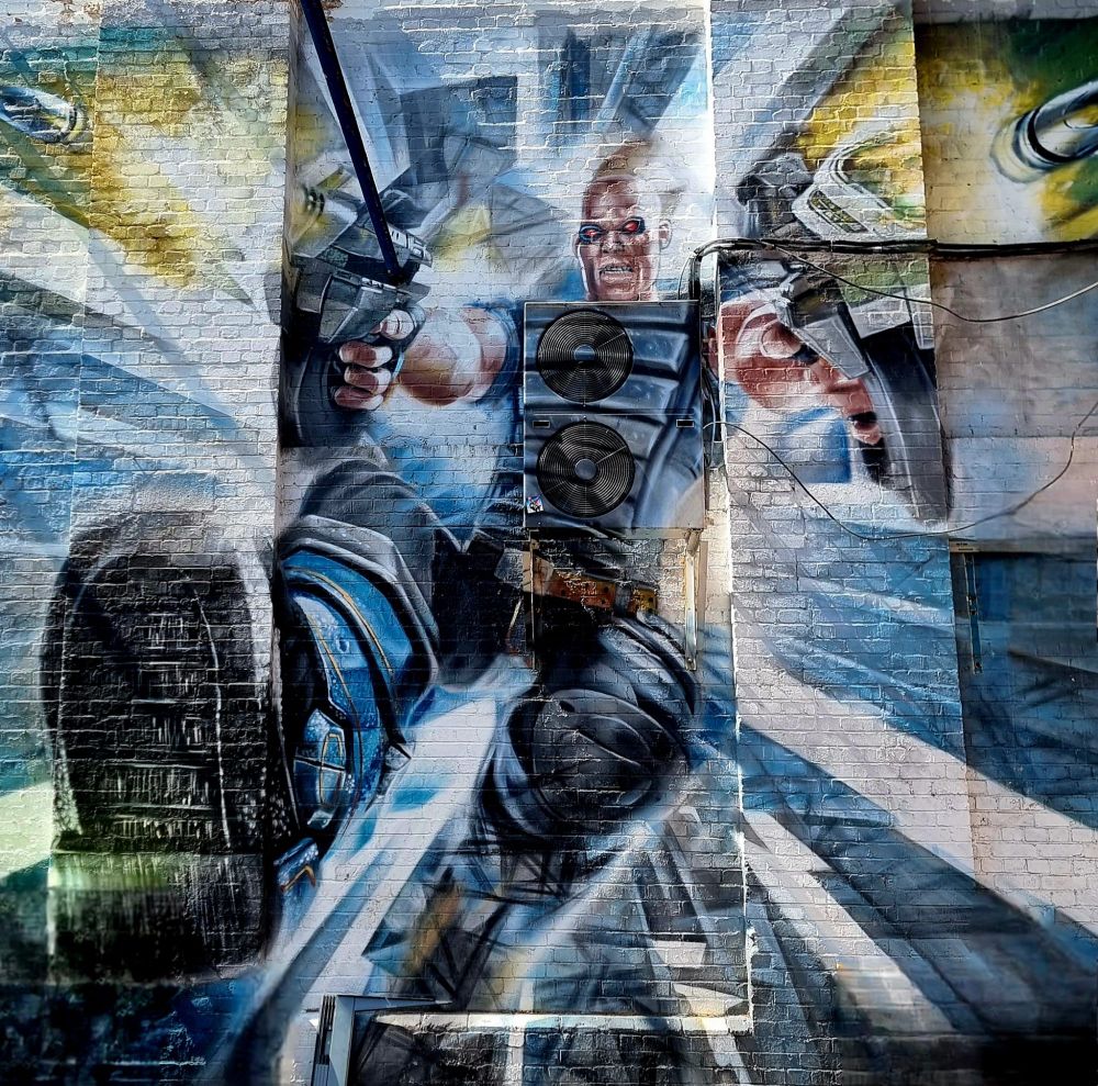 A character flying backwards through the air with guns out in front, firing is painting on a wall.