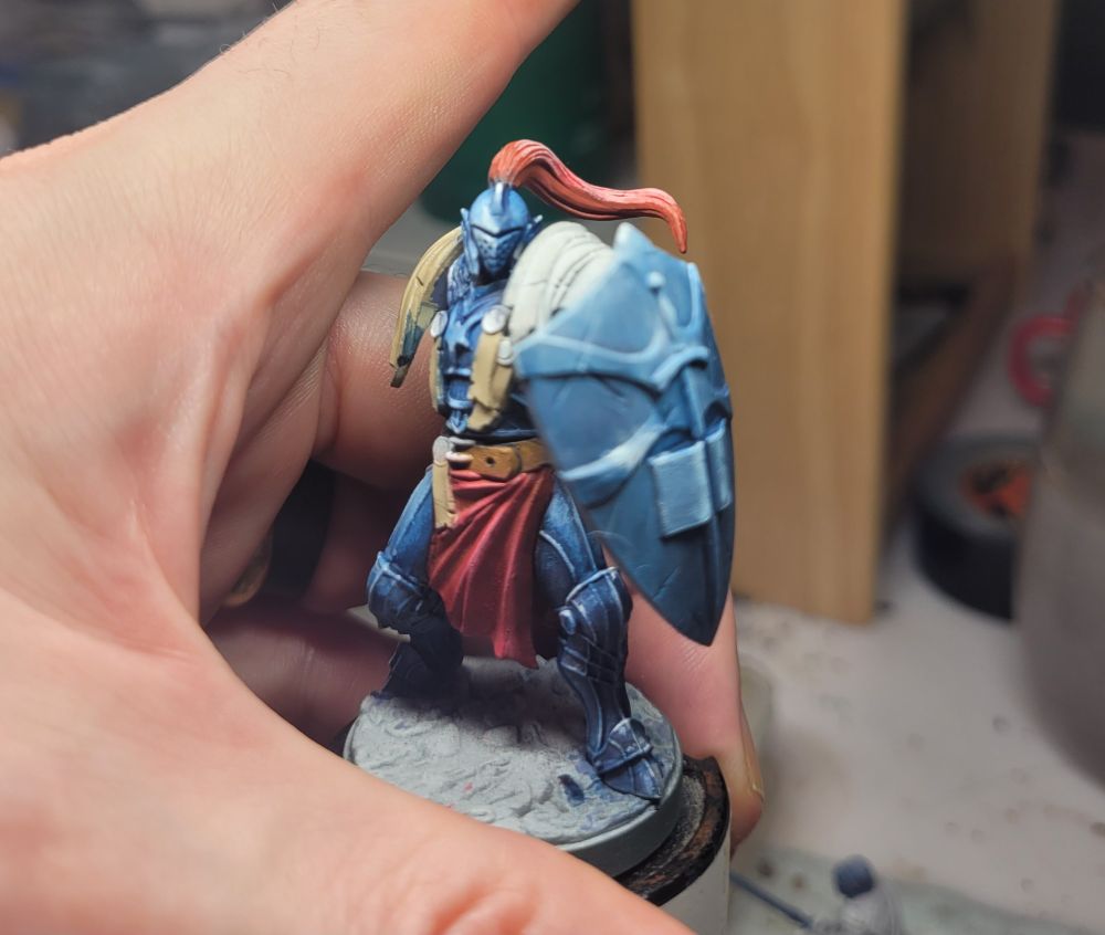 A gaming figure in the process of being painted. It is a knight with a shield.