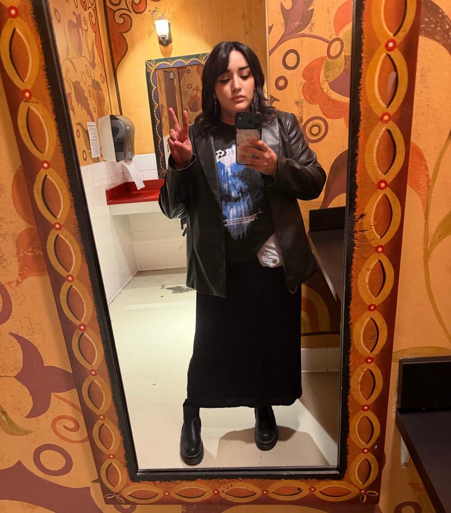 A picture of slime in a black skirt, tshirt, leather jacket and the peace sign she does in every fucking picture cause she doesn’t know what to do with her hands 