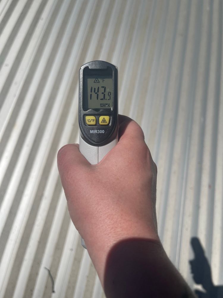 A capo points a digital thermometer at the main stage, showing a temperature of 143*f