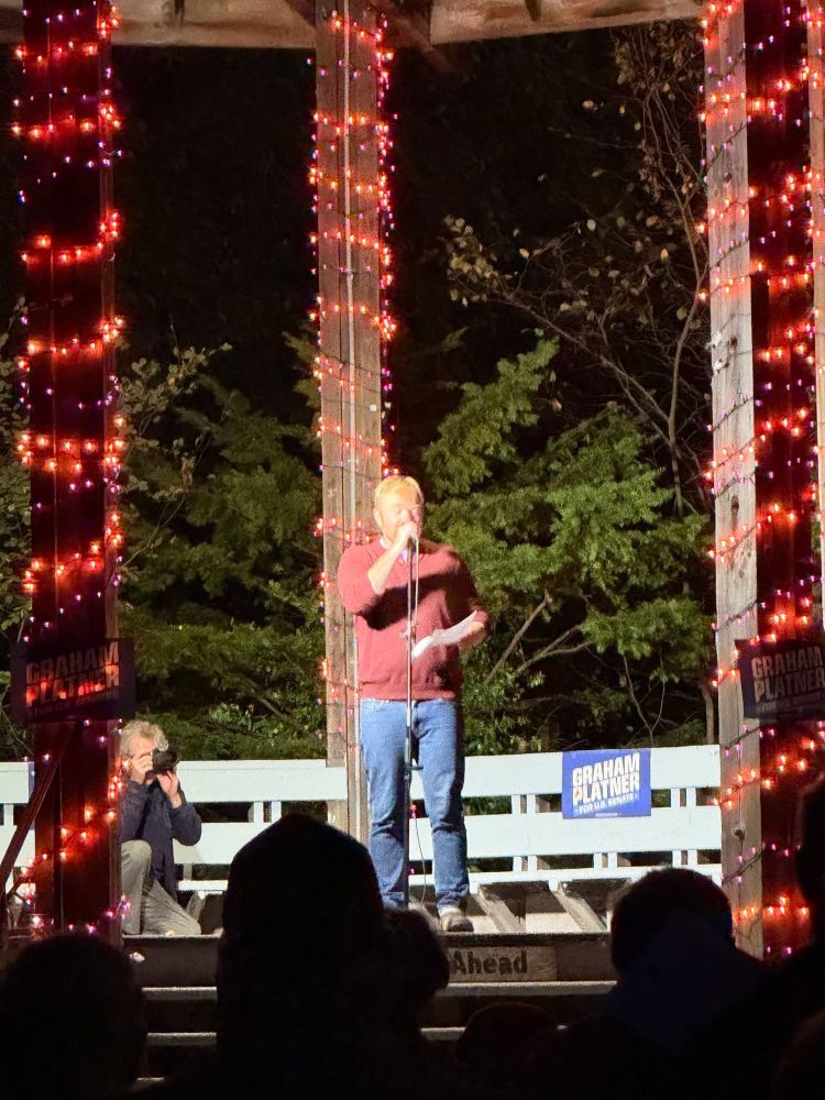 A picture of Graham Platner on a stage holding a microphone 