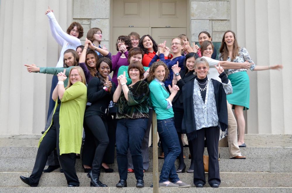 A group of women striking funny poses in front of a university building 