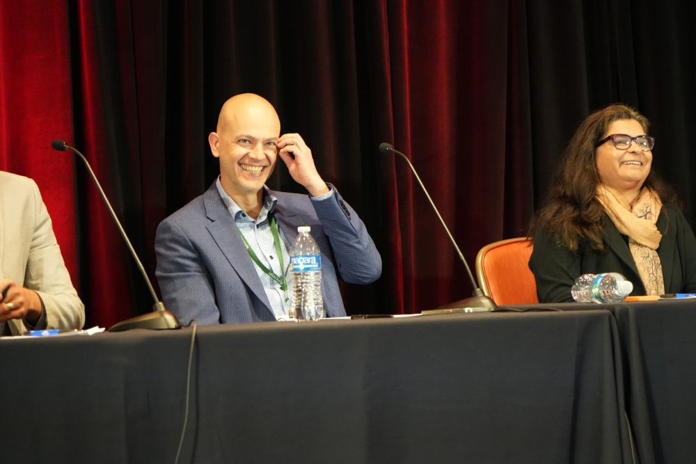 Two members of the panel are pictured smiling after hearing the audience member's comments.