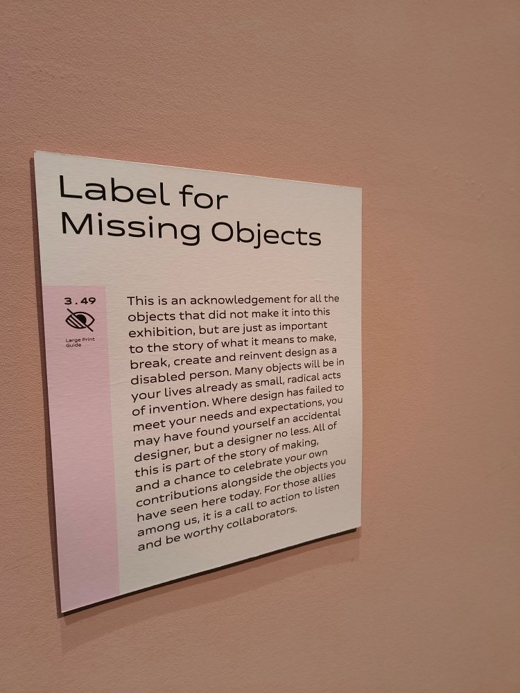 A wall sign on a light pink wall with the following text

Label for Missing Objects

This is an acknowledgement for all the objects that did not make it into this exhibition, but are just as important to the story of what it means to make, break, create and reinvent design as a disabled person. Many objects will be in your lives already as small, radical acts of invention. Where design has failed to meet your needs and expectations, you may have found yourself an accidental designer, but a designer no less. All of this is part of the story of making, and a chance to celebrate your own contributions alongside the objects you have seen here today. For those allies among us, it is a call to action to listen and be worthy collaborators.