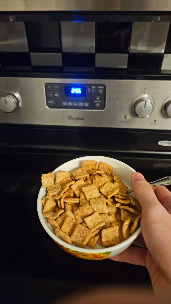 a bowl of cinnamon toast crunch in front of an oven with the clock reading 2:55