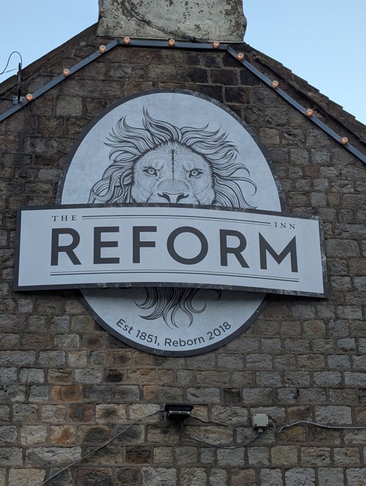 Pub sign reading "The Reform Inn" with a lion's head in the background 