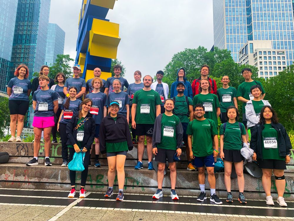 A diverse group of young people in running gear pose smiling next to the Euro sculpture.