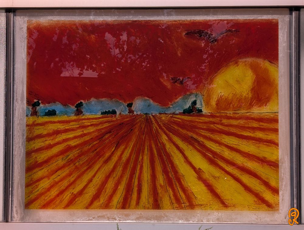 Painting of a farm field in extreme perspective, displayed on a community center window. The red and orange alternating till lines beckon you to the far away farm houses. The sky is an angry red rust tone as if the world is on fire on what can only be a hot Summer day. Two birds fly in that sky. Where the only reprieve is the green-blue slim line of forest in the horizon.