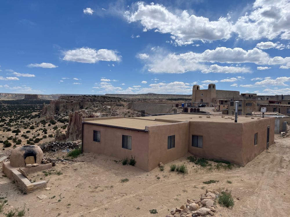 View of adobe village atop a desert mesa overlooking a valley full of rock formations