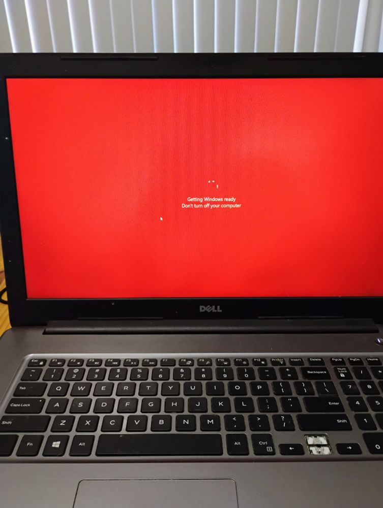 Red laptop screen saying "Getting Windows ready / Don't turn off your computer." The red screen is the result of personal customization.