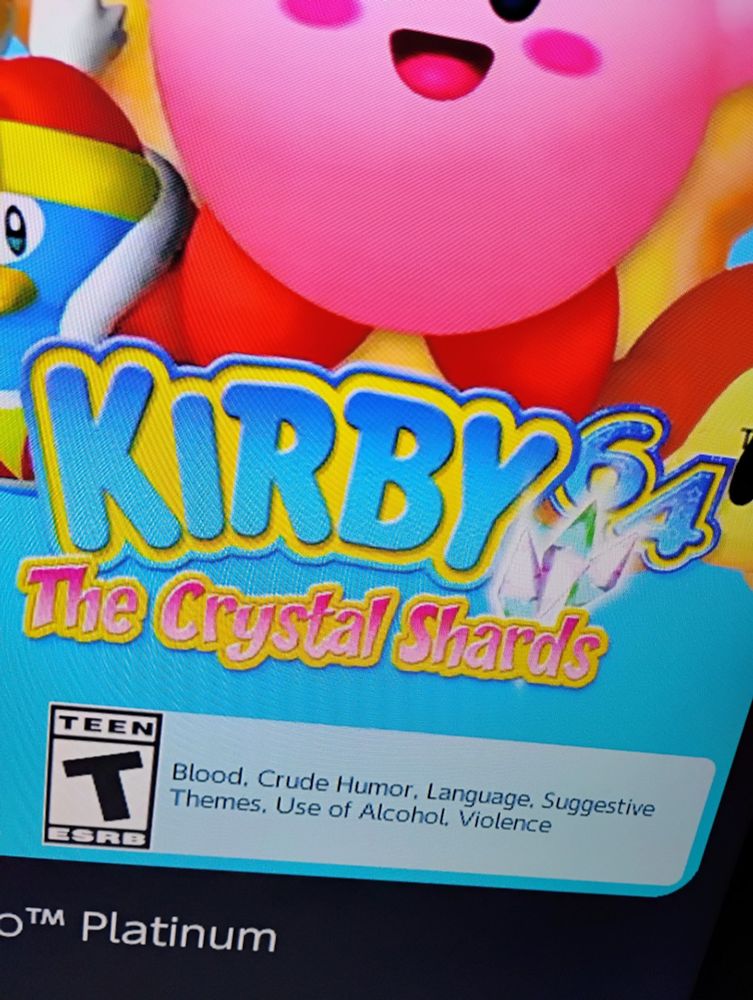 A screen featuring Kirby 64: The Crystal Shards juxtaposed above an ESRB T rating for "Blood, Crude Humor, Language, Suggestive Themes, Use of Alcohol, Violence."