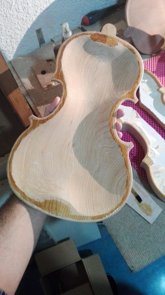 Mano sosteniendo el fondo de un violín con pegamento, Listo pata ser pegado al molde