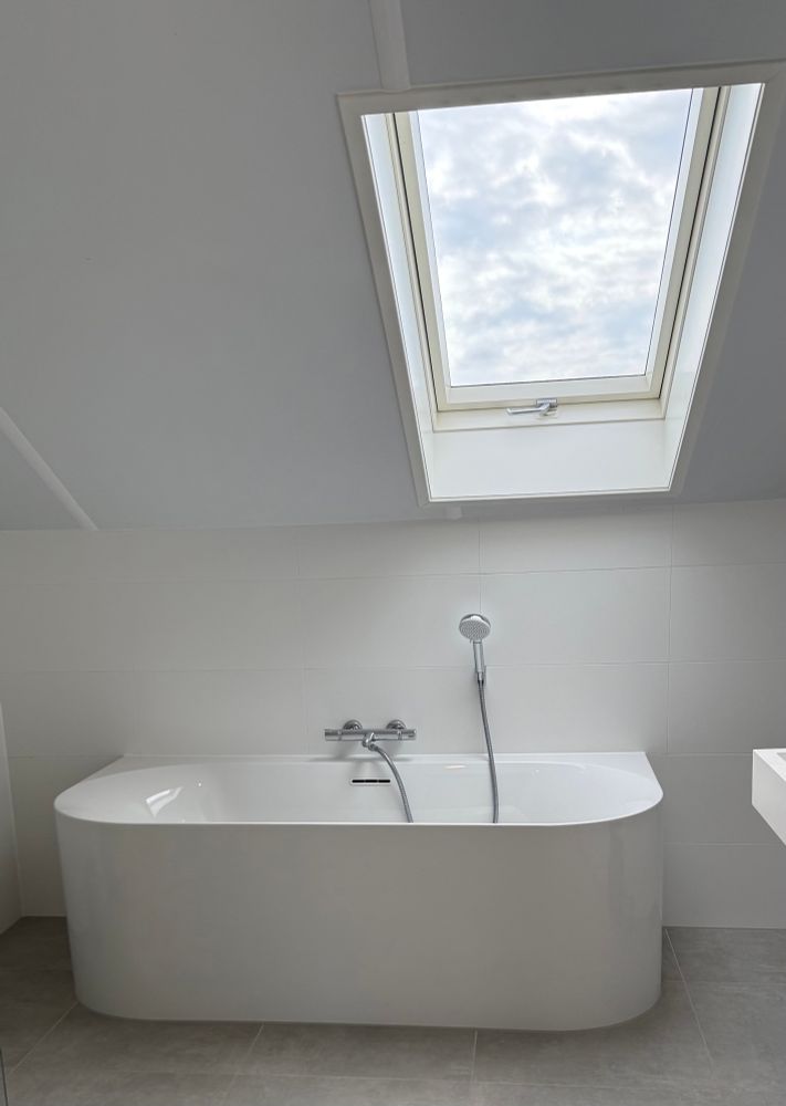 Weiße Wanne in weiss gestrichenem Raum mit Dachfenster 