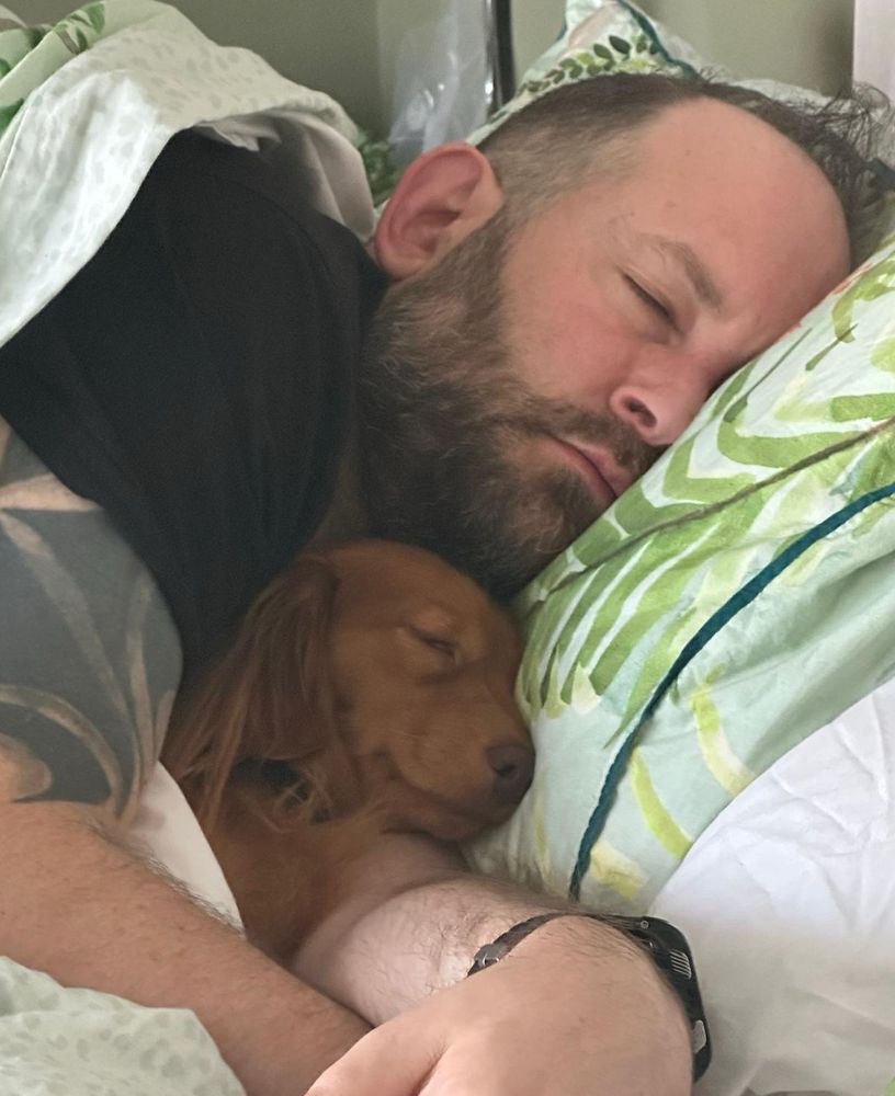 Sleeping man with sleeping puppy.