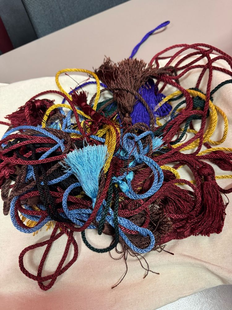 A bundle of coloured hat tassels waiting for graduation ceremonies … colours include burgundy, blue, yellow and brown. 