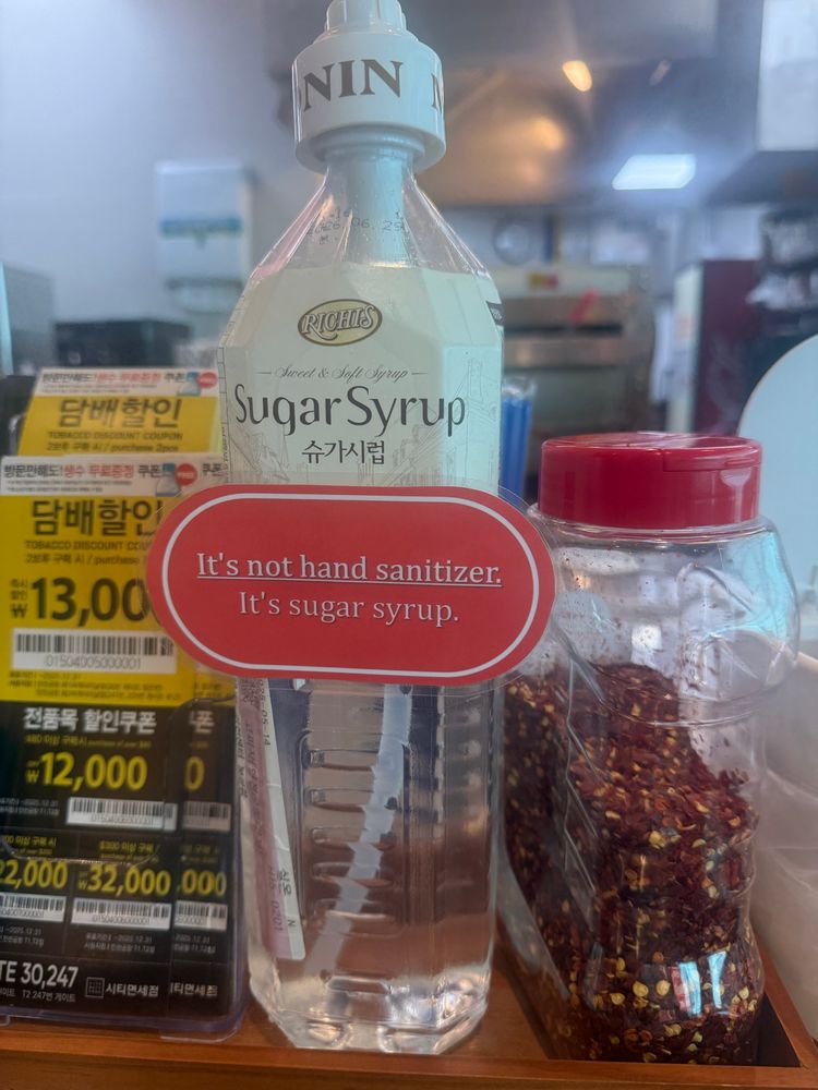 A large bottle of sugar syrup by the condiments at a till (in a pizza place in a Korean airport) that is clearly marked “sugar syrup” has a red sign on it that says “It’s not hand sanitiser, It’s sugar syrup.”

The “It’s not hand sanitiser” is underlined, which makes me read it in a very tired voice.
