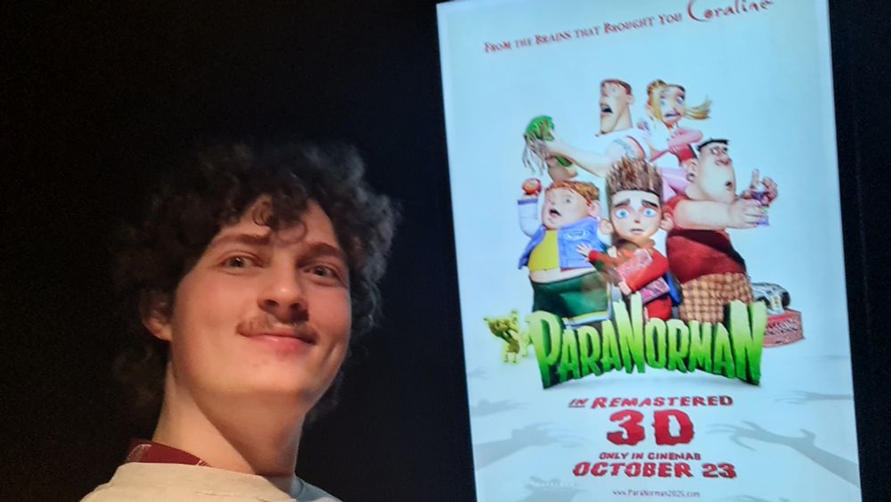Me standing with a screen poster for the ParaNorman anniversary re-release
