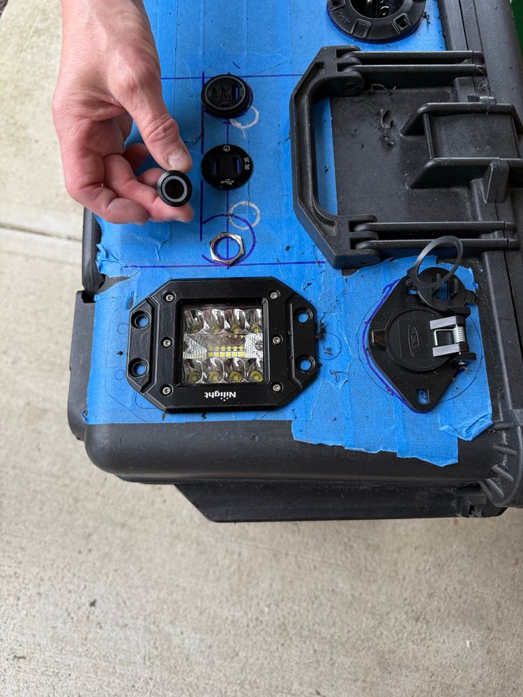 Solar generator - black box with blue tape. Hand holding  start button. Plugs and switches 