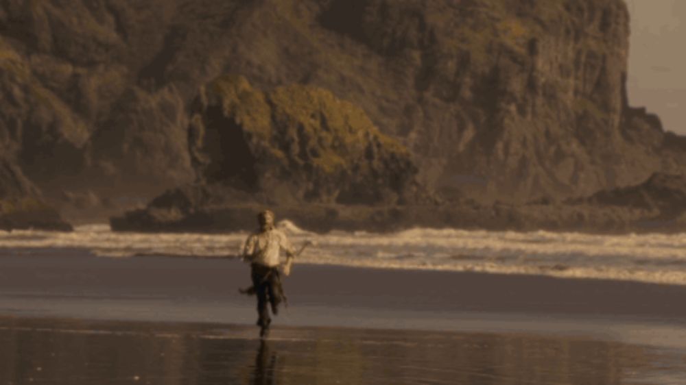 a man in a wetsuit is running on a beach