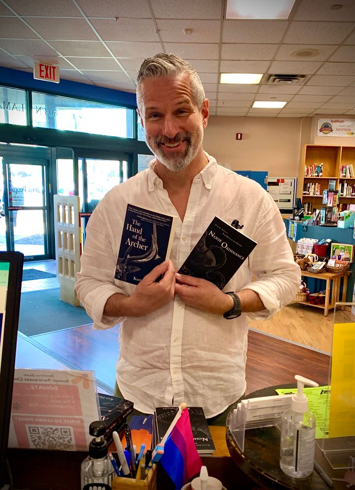 Author Kurt Phillips with his novels The Hand of the Archer & Noise Ordinance.