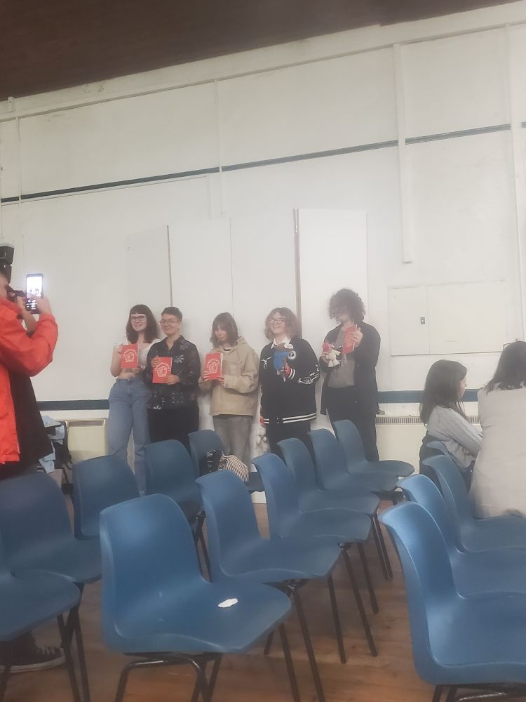 Five teenage contributors to Rainbow Library pose for a photograph in a school hall