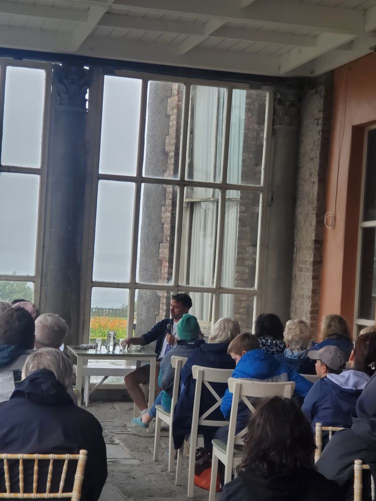 Will Sliney, seated, speaks to an audience in a sheltered area outside Bantry House.