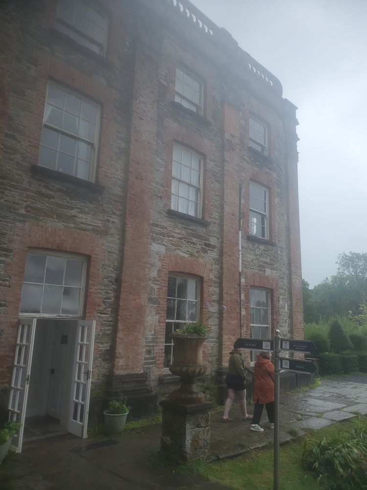 Bantry House, a lovely old three-storey building with bricks in warm colours. My buddies Caoimhe Hennessy and Anna Higgons walk along in front of it.