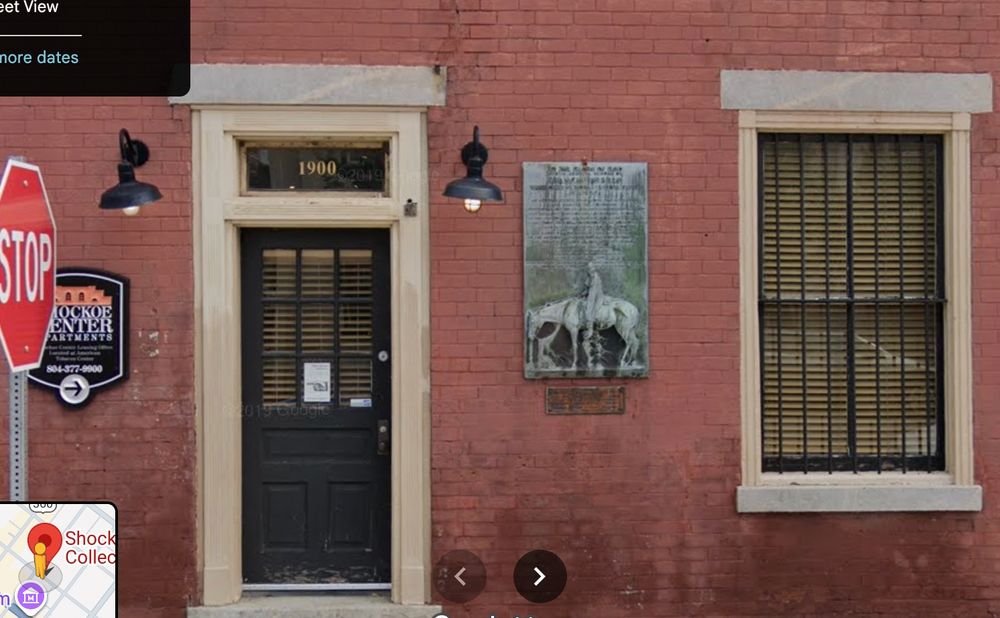 Close up of a brick building with a door, a window, and an unloved plaque commemorating Francis Asbury. 