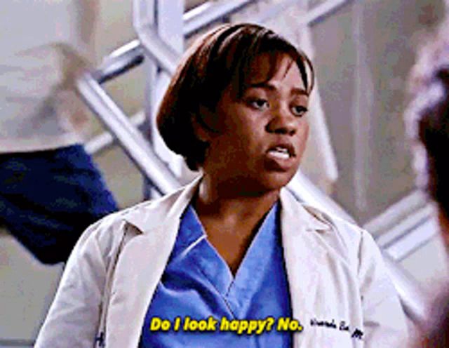 a woman in a white coat and blue scrubs says do i look happy no