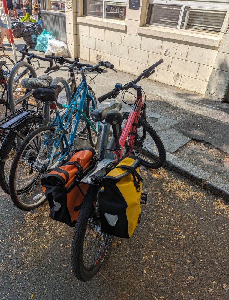 Red mountain bike with orange and yellow panniers. Parked alongside several other bikes