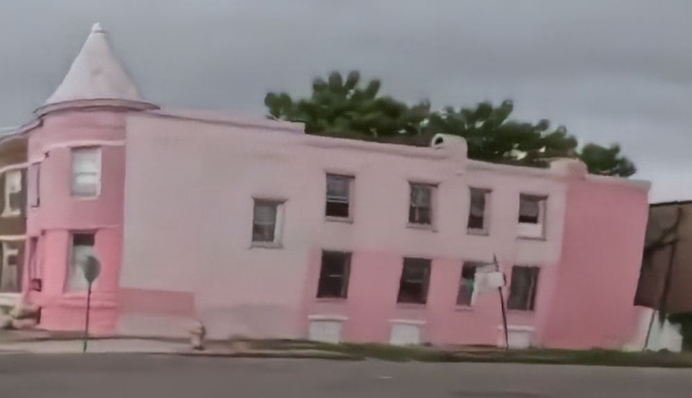 A screenshot of a rowhouse painted two shades of pink, a dark and light shade of pink